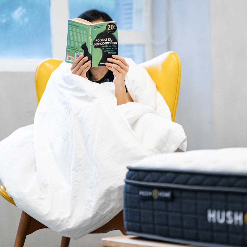 一位女士裹在全香港最好的 Hush Home 重力被中舒適地閱讀書籍 